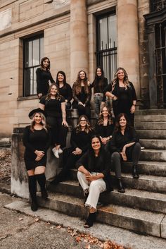 a group of women in black outfits posing for a photo on the steps of an old building