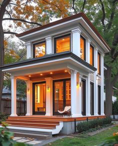 a small white house with lots of windows and steps leading up to the front door