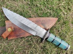 a knife is laying on the ground next to a leather sheath with a green handle