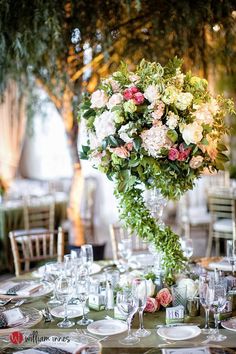 a vase filled with flowers sitting on top of a table covered in plates and glasses