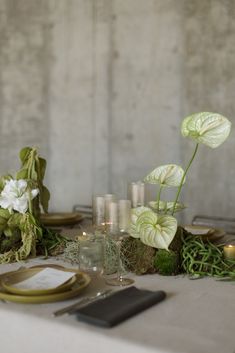 the table is set with candles, flowers and greenery for an elegant wedding reception