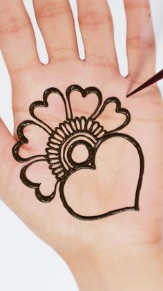 a person's hand with a henna tattoo on it and a heart drawn on the palm