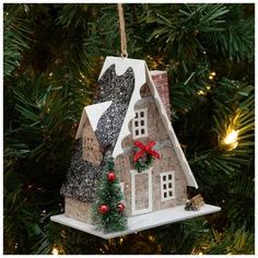 a house ornament hanging from a christmas tree