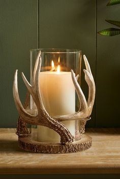 an antler candle holder with a lit candle in it