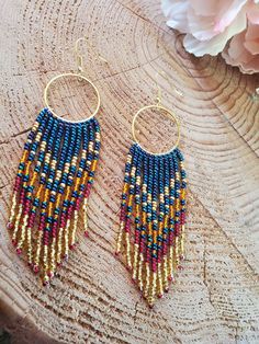 the beaded earrings are hanging from gold hoops with blue and red beads on them