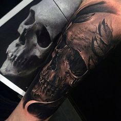 a man's arm with a skull and feathers tattoo on it