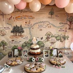 a table topped with cakes and desserts under balloon strings in front of a map