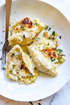 a white plate topped with ravioli covered in cheese