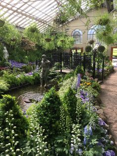 an indoor garden filled with lots of flowers and greenery next to a small pond