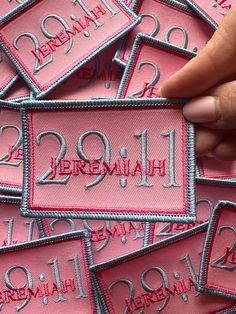 someone is stitching the number and name on their pink patched garment with silver thread