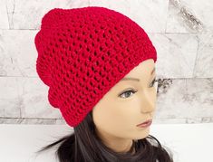 a mannequin head wearing a red crocheted hat on top of a wig