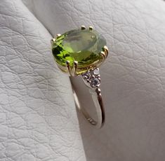 "This beautiful engagement ring is hand made in 14k yellow center and 14k white solid gold band. The natural Peridot weight is 4.02 cts and prong set in the 14k yellow gold. The Peridot measurements are 11mm x 8.9mm. The 6 side diamonds are VS-SI clarity and H color range .12cts total weight . Total gem weight is 4.14cts. We can make it any size from 5-7 and you still be able to return it within the listed time frame. Sizing outside of that range requires a resize fee if for any reason the ring Luxury Hallmarked Peridot Jewelry, Fine Jewelry Peridot Gemstones For Formal Occasions, Elegant Peridot Gemstones For Anniversary, Classic Peridot Diamond Ring Gift, Classic Peridot Diamond Ring For Gift, Oval Peridot Gemstones For Anniversary, Hallmarked Oval May Birthstone Gemstones, Van Nuys, Vintage Fine Jewelry