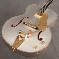 a white and gold guitar sitting on top of a table