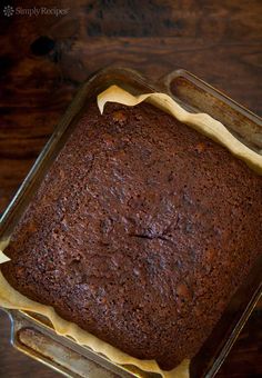 a chocolate cake in a glass pan on a wooden table