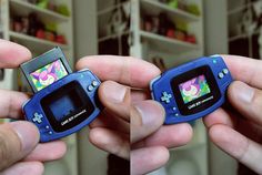 two hands holding small video game systems in front of each other with colorful images on them