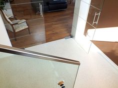 a bathroom with a glass door and wooden flooring next to a bathtub in the corner