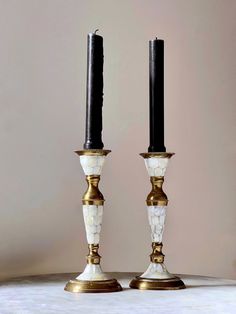 two white and gold candlesticks sitting next to each other