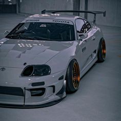 a white toyota sports car parked in a parking garage with its hood up and the front bumper down