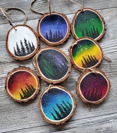 six wood slice ornaments with trees painted on them