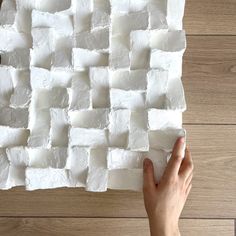 a person is holding a piece of white paper on top of a wooden table with squares