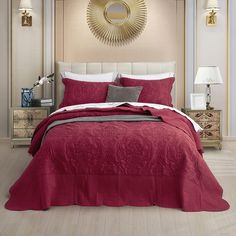 a bed with red bedspread and pillows in a room