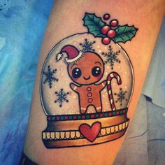 a christmas themed tattoo with a ginger in a snow globe and candy canes on the arm