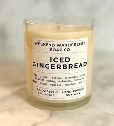 an iced gingerbread candle sits on a marble countertop next to a bottle of hand - poured soap