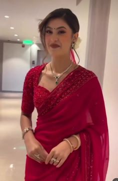 a woman in a red sari posing for the camera with her hands on her hips