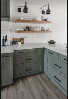 a kitchen with gray cabinets and white counter tops, wooden shelves above the stovetop