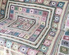 a crocheted blanket with squares and flowers on it