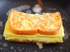 a grilled cheese sandwich sitting on top of a black pan with water droplets around it