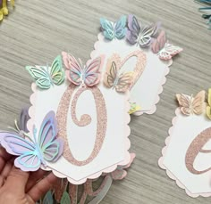 someone is holding up some paper butterflies to cut out the number six and butterfly wings