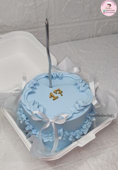 a blue cake in a white box with a silver fork sticking out of the top