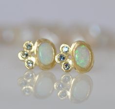 "Opal gold earrings, 18k gold bezel, 14k gold wire, oval Opal and light green small Sapphires. Unique dainty stunning dangle earrings. Flower shape: beautiful oval Opal sets in 18k gold bezel, with 3 light green Sapphires set in three tiny leaves. I find the combination between the 18k gold the green Sapphires and the Opal extraordinary. These earrings can be the perfect earrings for a bride with her white dress and her big smile on her special day. You can wear these earrings every day, with a Oval Yellow Gold Earrings With Rose Cut Diamonds, Yellow Gold Earrings With Bezel Setting For Wedding, Earring For Bride, Green Sapphire Earrings, Bridal Dangle Earrings, Sapphire Earring, Earrings For Bride, Opal Earring, Blue Sapphire Earrings