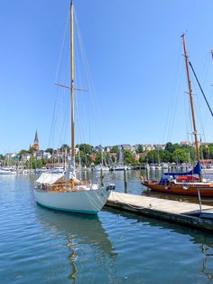 two sailboats are docked in the water next to each other on a sunny day