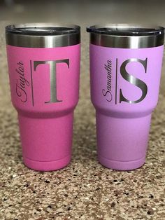 two pink and purple tumblers sitting on top of a counter