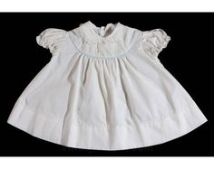 An innocent little frock for your little innocent!  This vintage dress has a Peter Pan collar rimmed in lace, puffed sleeves and adorable embroidered daisies to the lapel & dress front.  Has two petite decorative buttons at the chest, blue piping along the yoke, and a scalloped skirt.   Child's Size  6 Months  Measurements  Chest 22; Neck to Hem 14 Inches  Era  1950s   Label  '' baby B . . . '' at back neck  Materials  White cotton broadcloth; baby blue cotton piping; white synthetic lace; w White Cotton 1950s Style Dress, 1950s White Cotton Dress, 1950s Style White Short Sleeve Dress, Vintage Cotton Baptism Dress, Baby In Wedding Dress, Embroidered Daisies, Newborn Baby Dresses, Lapel Dress