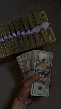 a hand is holding money in front of stacks of bills