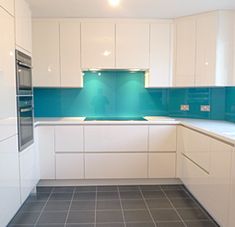 an empty kitchen with white cabinets and blue backsplash tiles on the flooring