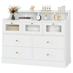 a white dresser with gold handles and drawers