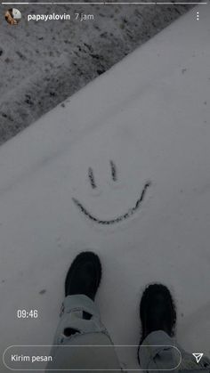 someone is standing in the snow with their feet on the ground and smiling at the camera