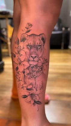 a woman's leg with a lion and flowers tattoo on it