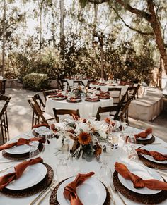 a table set with plates and place settings for an outdoor wedding reception in the woods