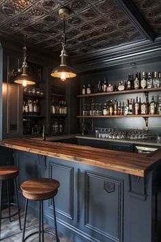 a bar with two stools in front of it and bottles on the shelves above