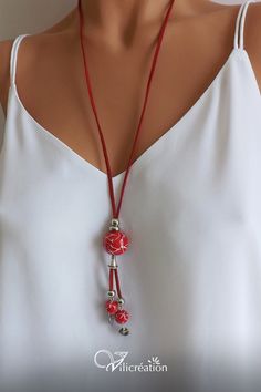 a woman wearing a white top and red necklace with beads on it's neck