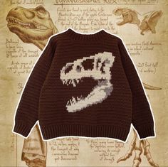 a knitted sweater with an image of a dinosaur's head on it, sitting in front of a drawing