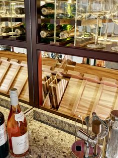 two bottles of wine sitting on top of a counter next to some glasses and silverware