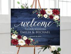 a welcome sign with flowers and greenery is displayed in front of a easel