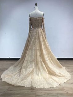 the back of a wedding dress on display in a room with wood flooring and white walls