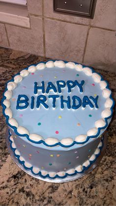 a blue birthday cake with white frosting and sprinkles sitting on a counter